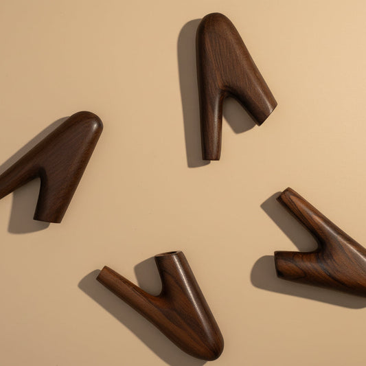 Four dark brown shoe tree shapes on a white background